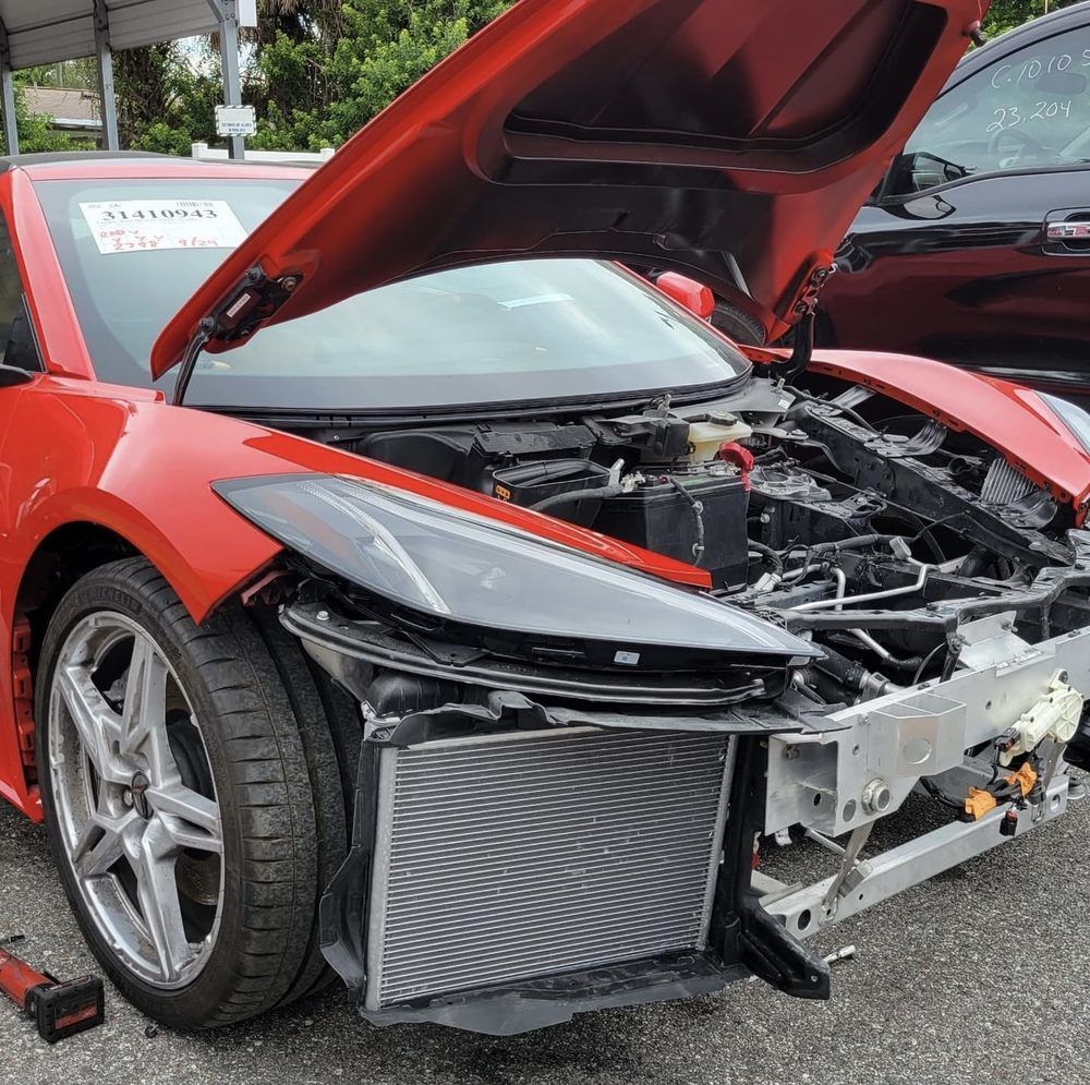 Red sports car with open hood, front end damage.