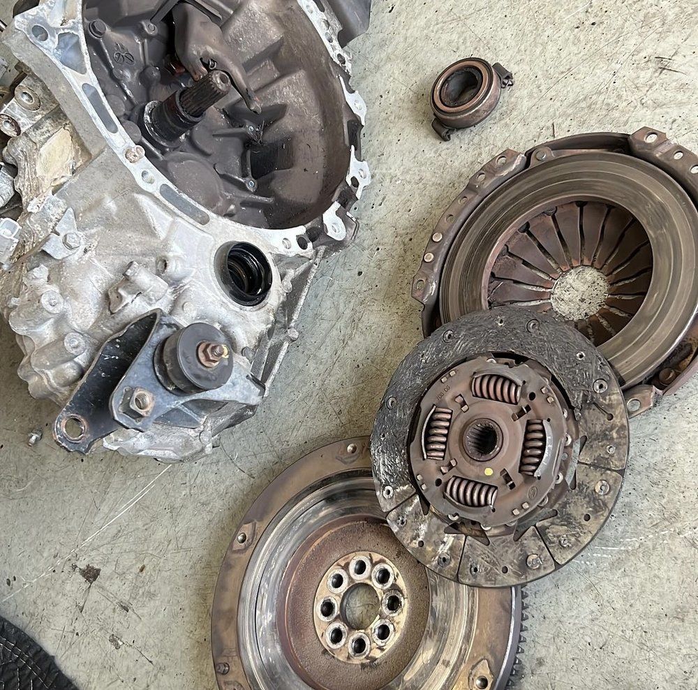 Car transmission and clutch components on a concrete surface.
