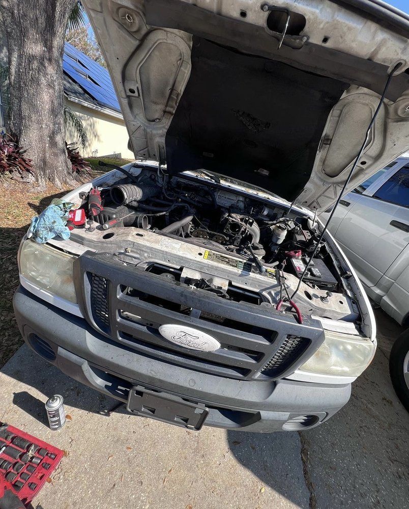Ford Ranger truck with open hood; engine repair in progress outdoors.