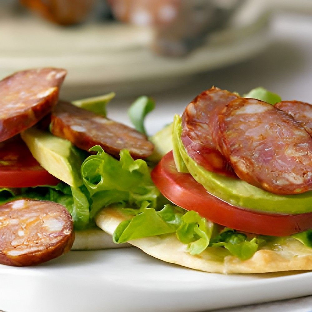 A Close Up of a Sandwich With Tomatoes Avocado and Sausage — Corrado & Frank Distributors in Illawarra, NSW