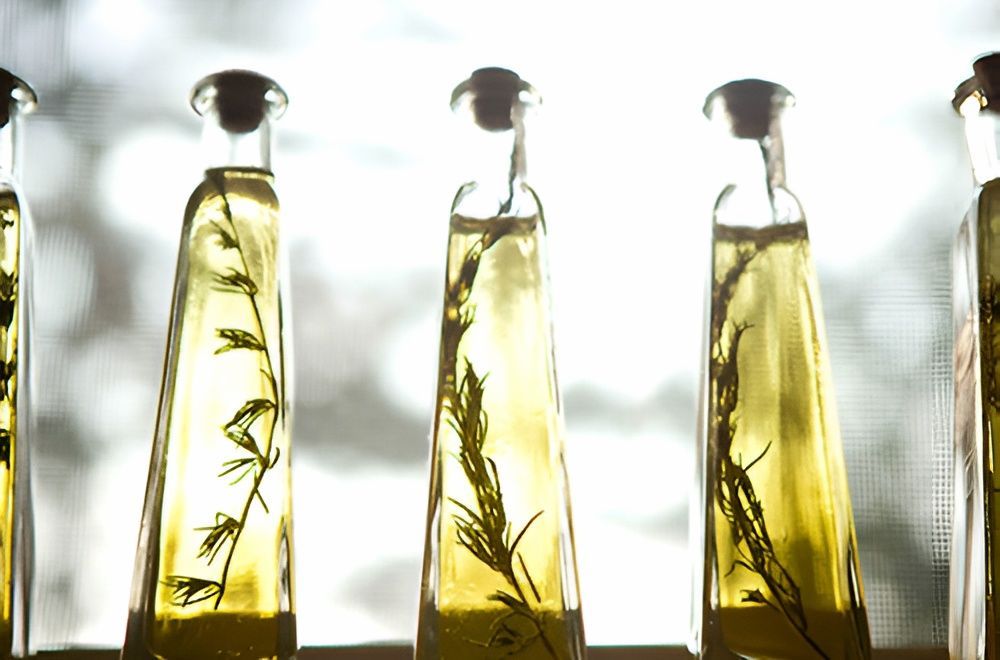 A Row of Bottles of Olive Oil With Herbs in Them — Corrado & Frank Distributors in Fairy Meadow, NSW