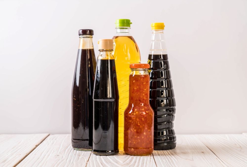 A Group of Bottles of Sauces Are Sitting on a Wooden Table — Corrado & Frank Distributors in Fairy Meadow, NSW