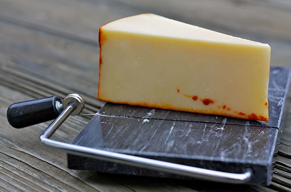 A Piece of Cheese is Sitting on a Marble Cutting Board  — Corrado & Frank Distributors in Fairy Meadow, NSW