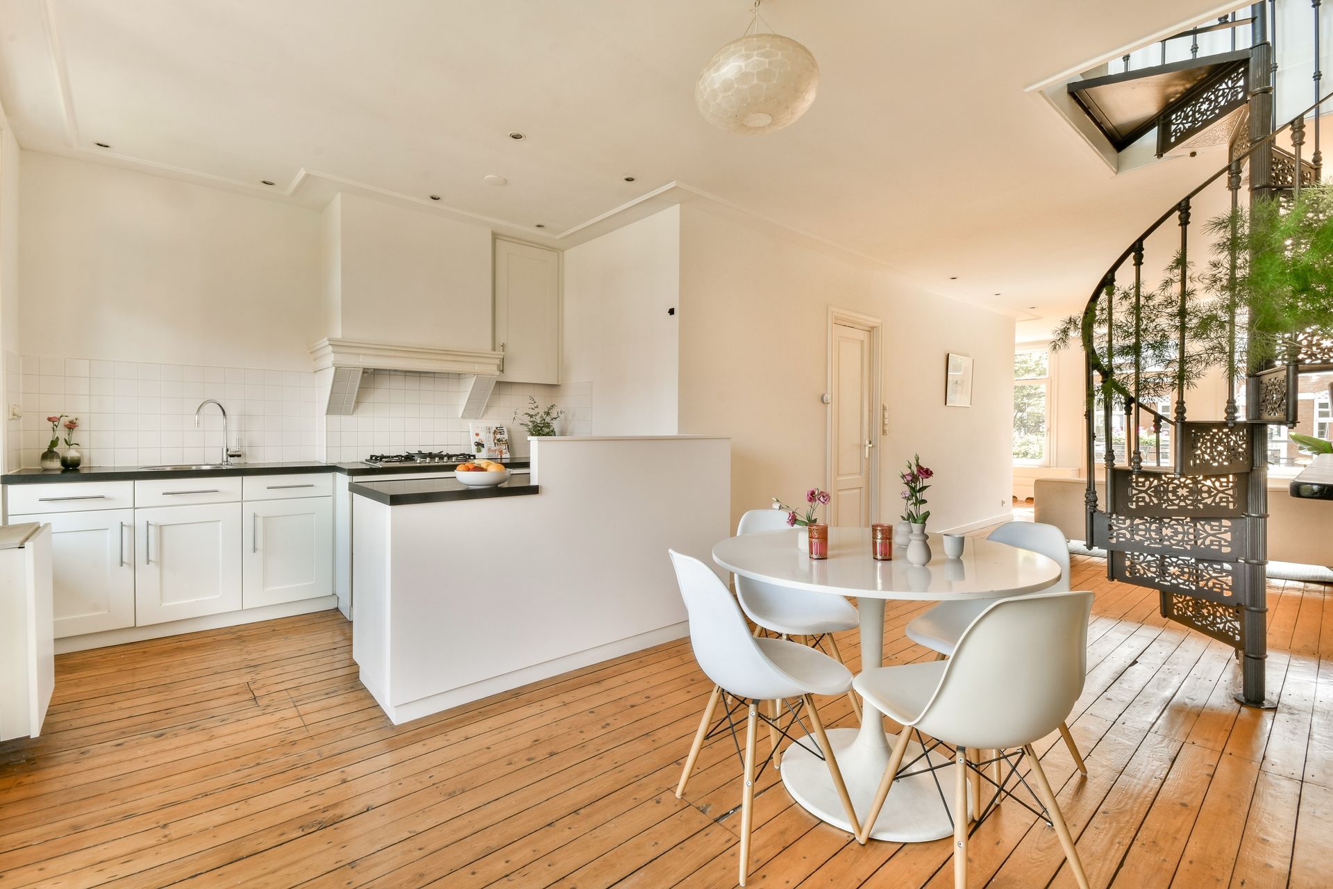 White kitchen with round table and chairs. Spiral staircase visible.