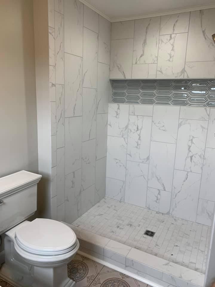 A bathroom with a toilet , shower and marble tiles.