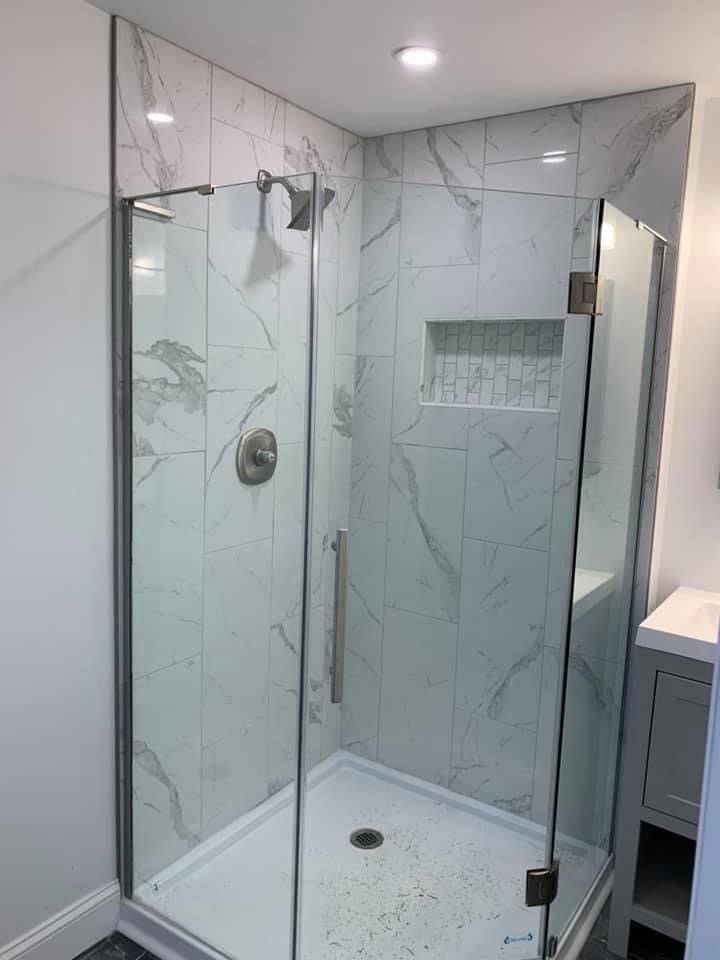 A bathroom with a walk in shower with a glass door.