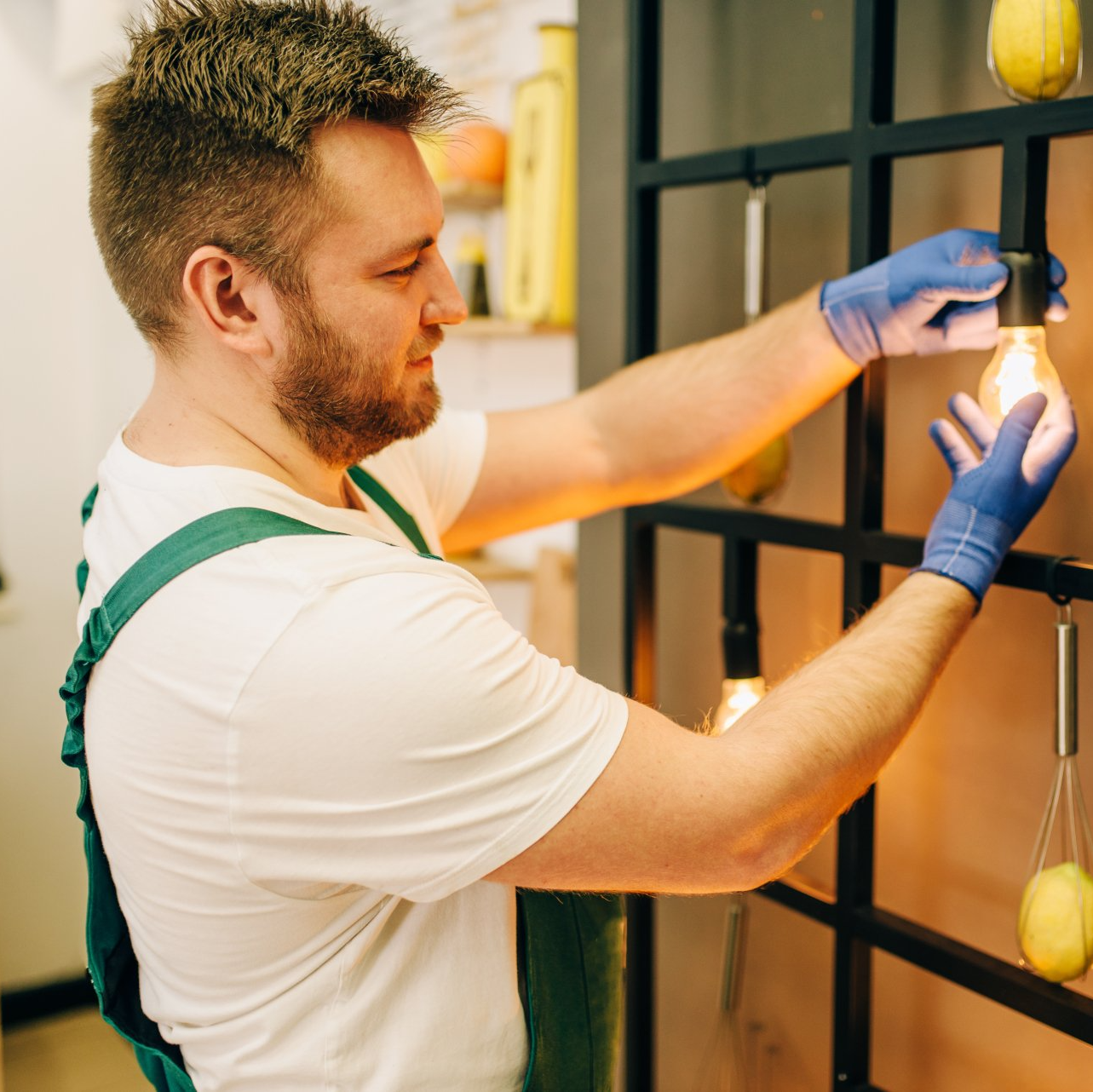 A man wearing blue gloves is fixing a light bulb