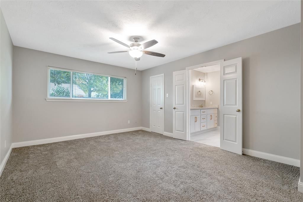 An empty bedroom with a ceiling fan and a window.