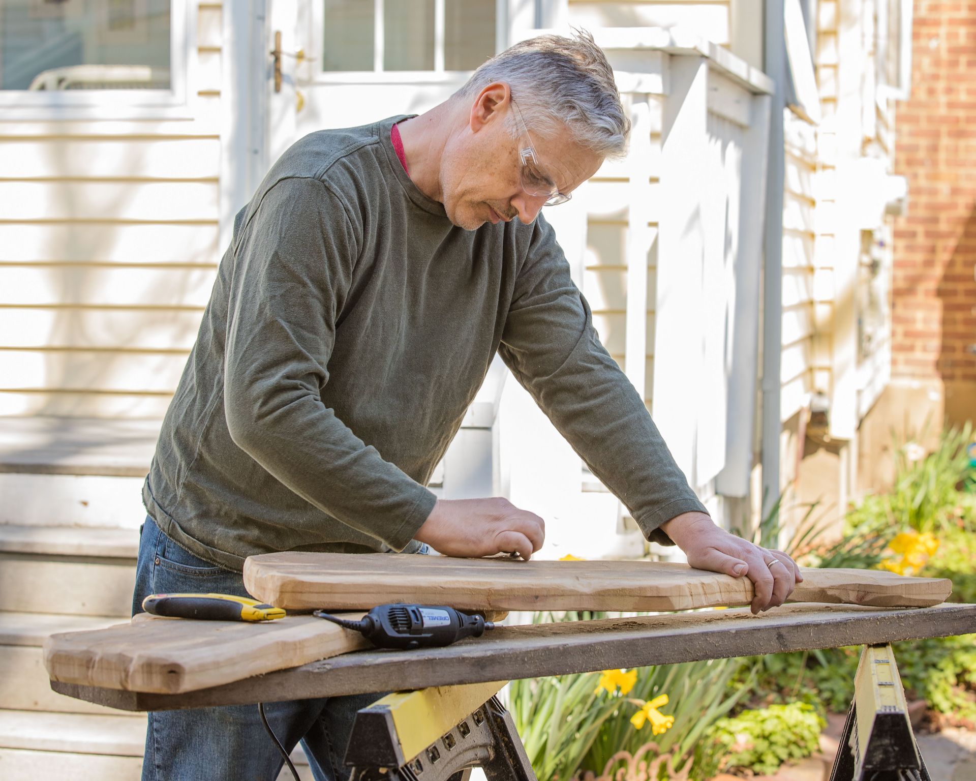 A man is working on a piece of wood on a workbench.