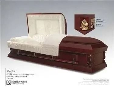 Open wooden casket with white interior and a corner cabinet holding a gold decorative piece.