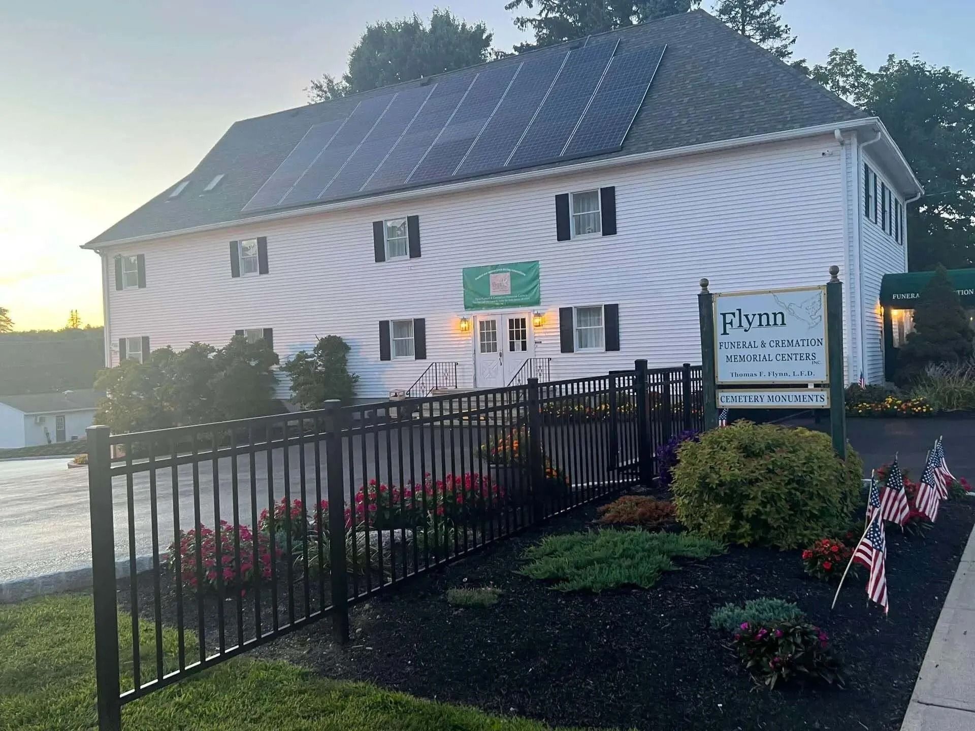 White two-story building with solar panels, a sign reading 