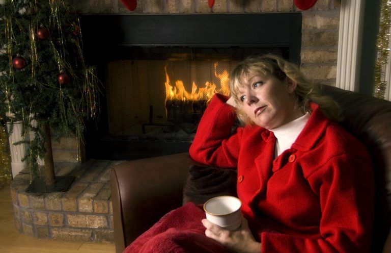 Grieving lady sitting by the fire during the holidays