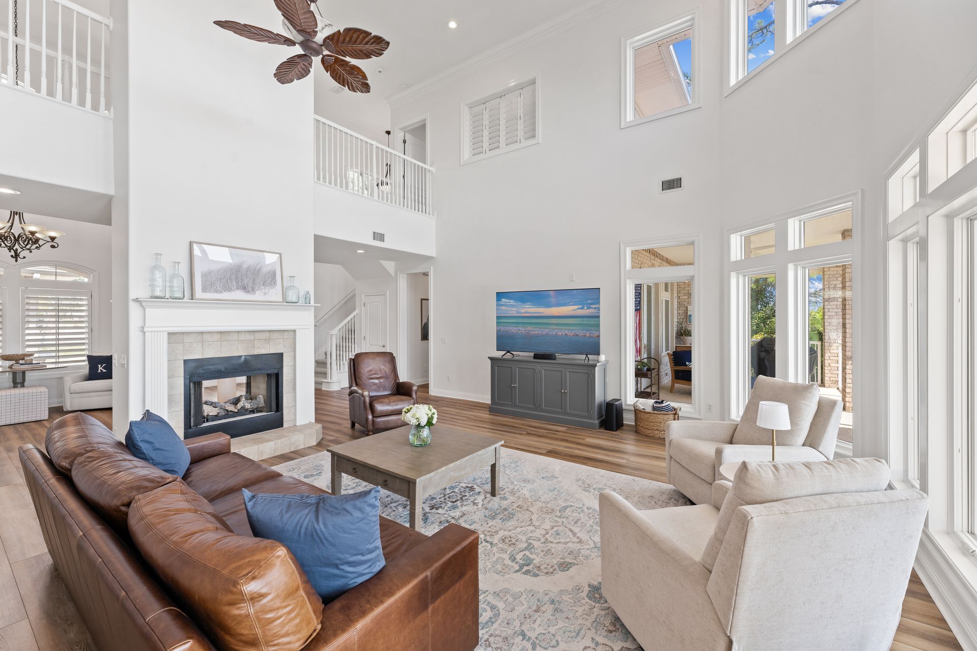 Spacious living room with high ceilings, fireplace, leather sofa, and large windows; light and airy.