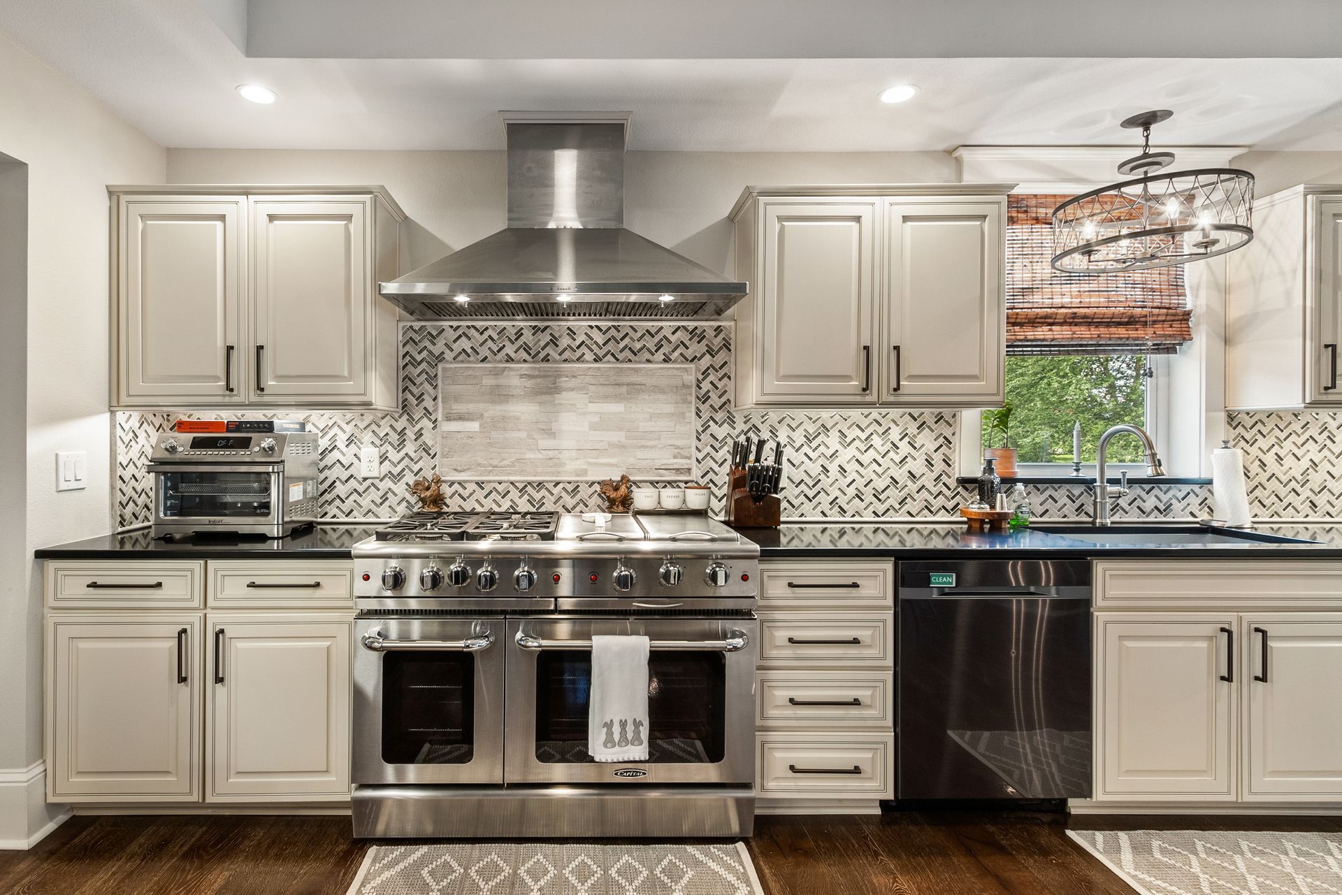 Modern kitchen with stainless steel appliances, light cabinets, and patterned backsplash.