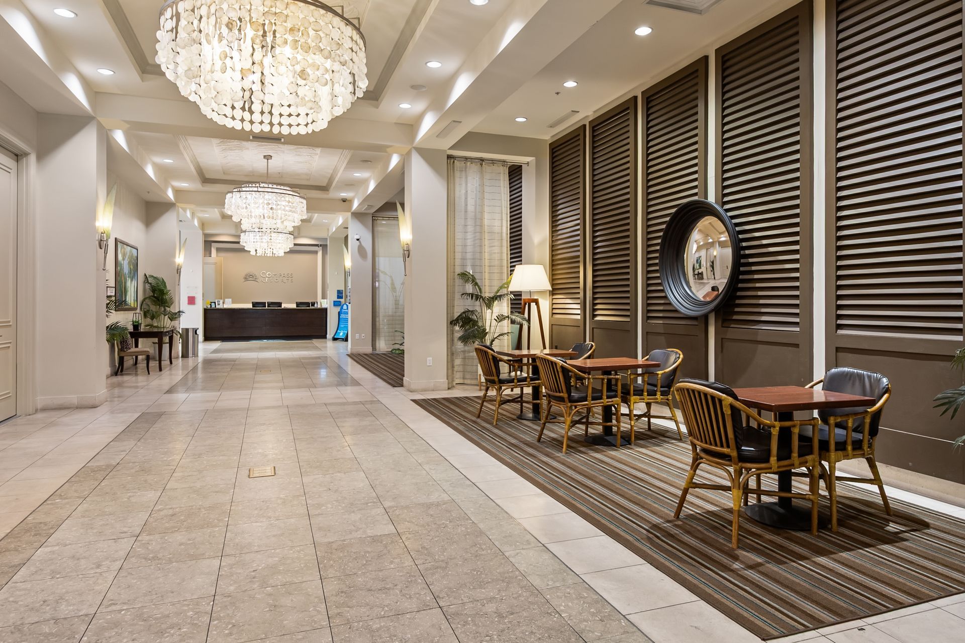 Hotel lobby with chandeliers, seating area, and reception desk.
