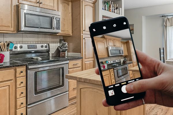 Someone taking a photo of a kitchen interior with their smart phone camera.
