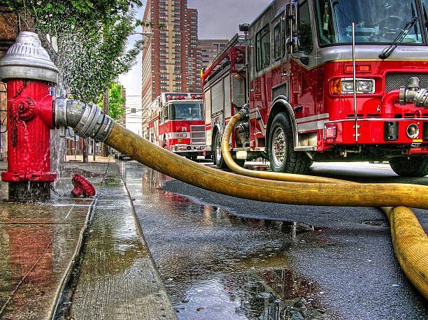 Fire trucks in action, deploying hoses connected to a fire hydrant.