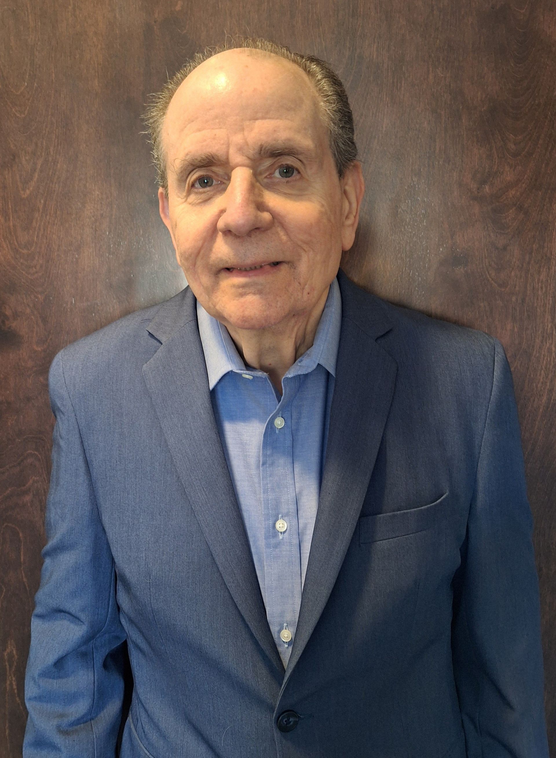 A man in a suit and tie is standing in front of a red background.