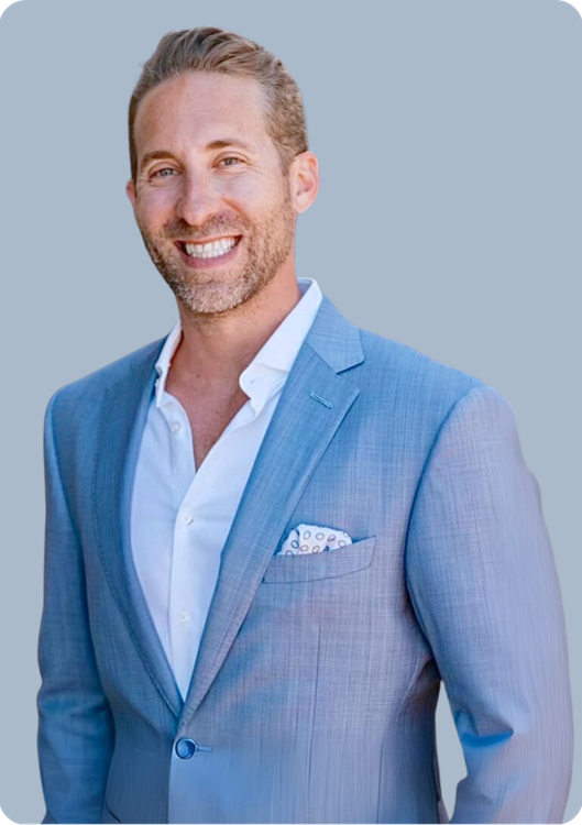 A man in a white shirt and tie is standing with his hands in his pockets.