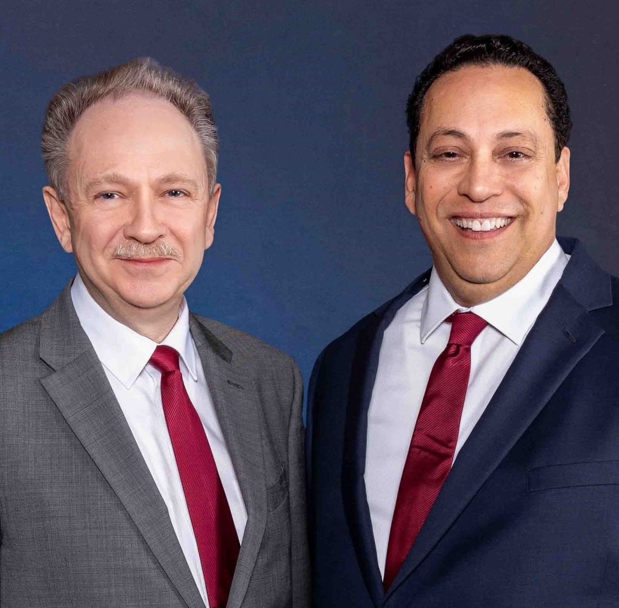 Two men in suits and ties are posing for a picture