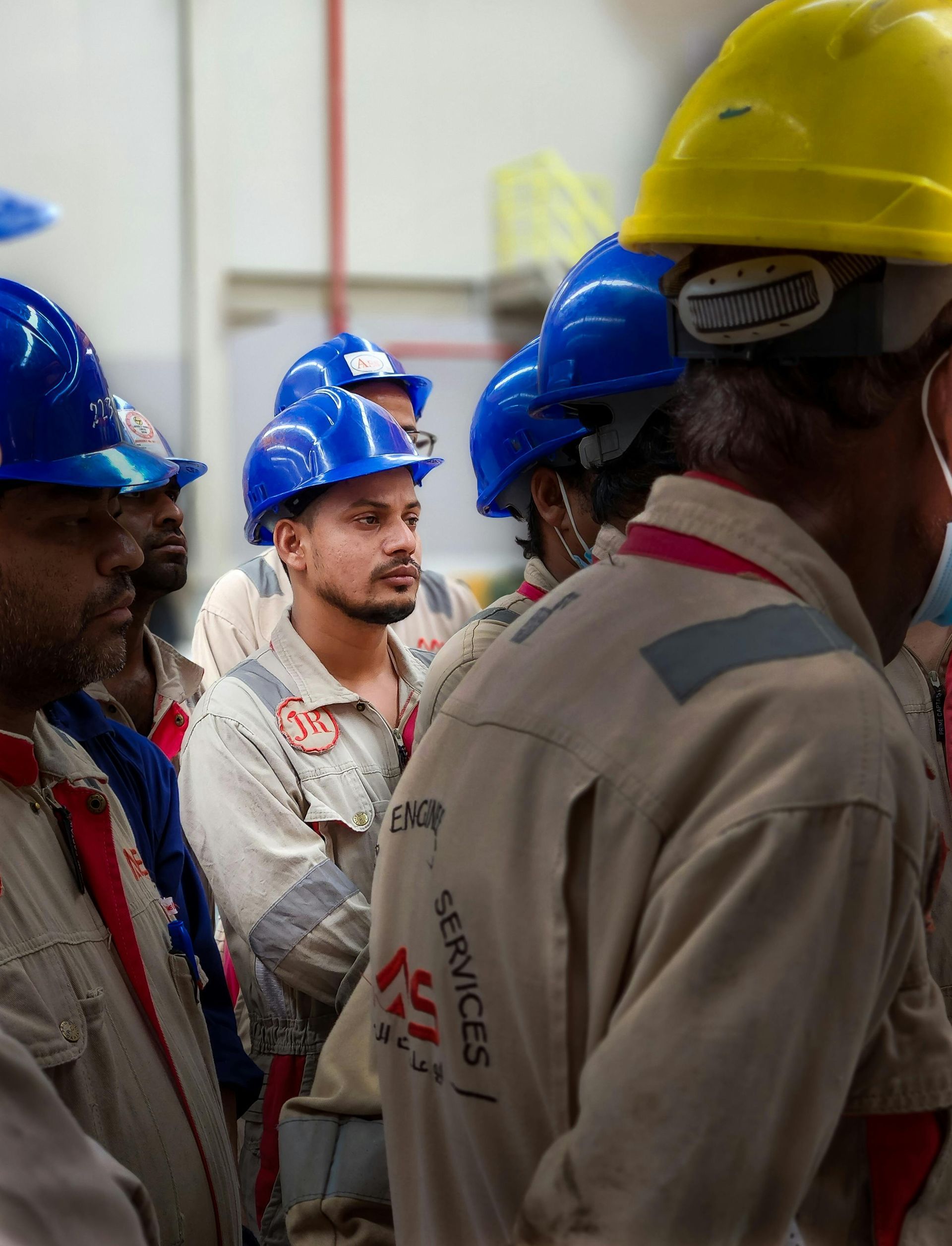 A group of men wearing hard hats are standing in a room