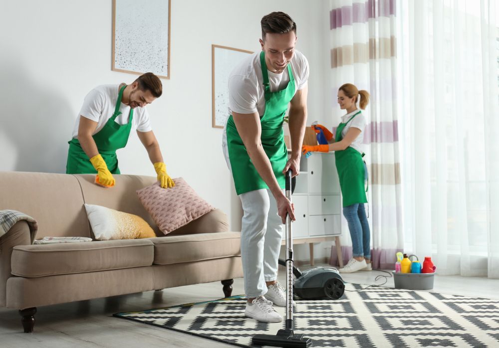 A man is using a vacuum cleaner to clean the floor in a living room.
