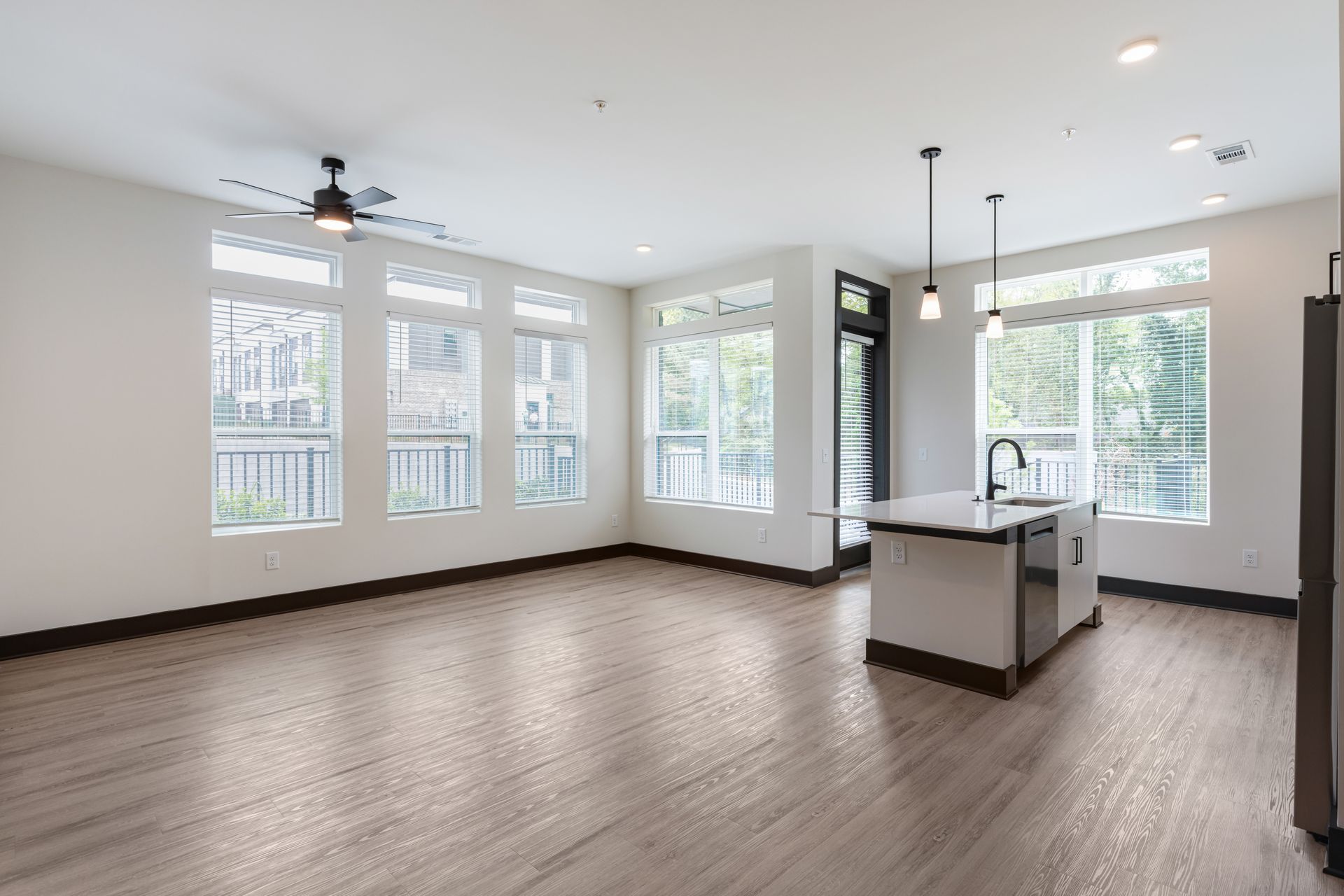 Spacious modern kitchen with large windows, white cabinets, island, and wood floors at Vela Park apartments in East Lake, Atlanta, GA.