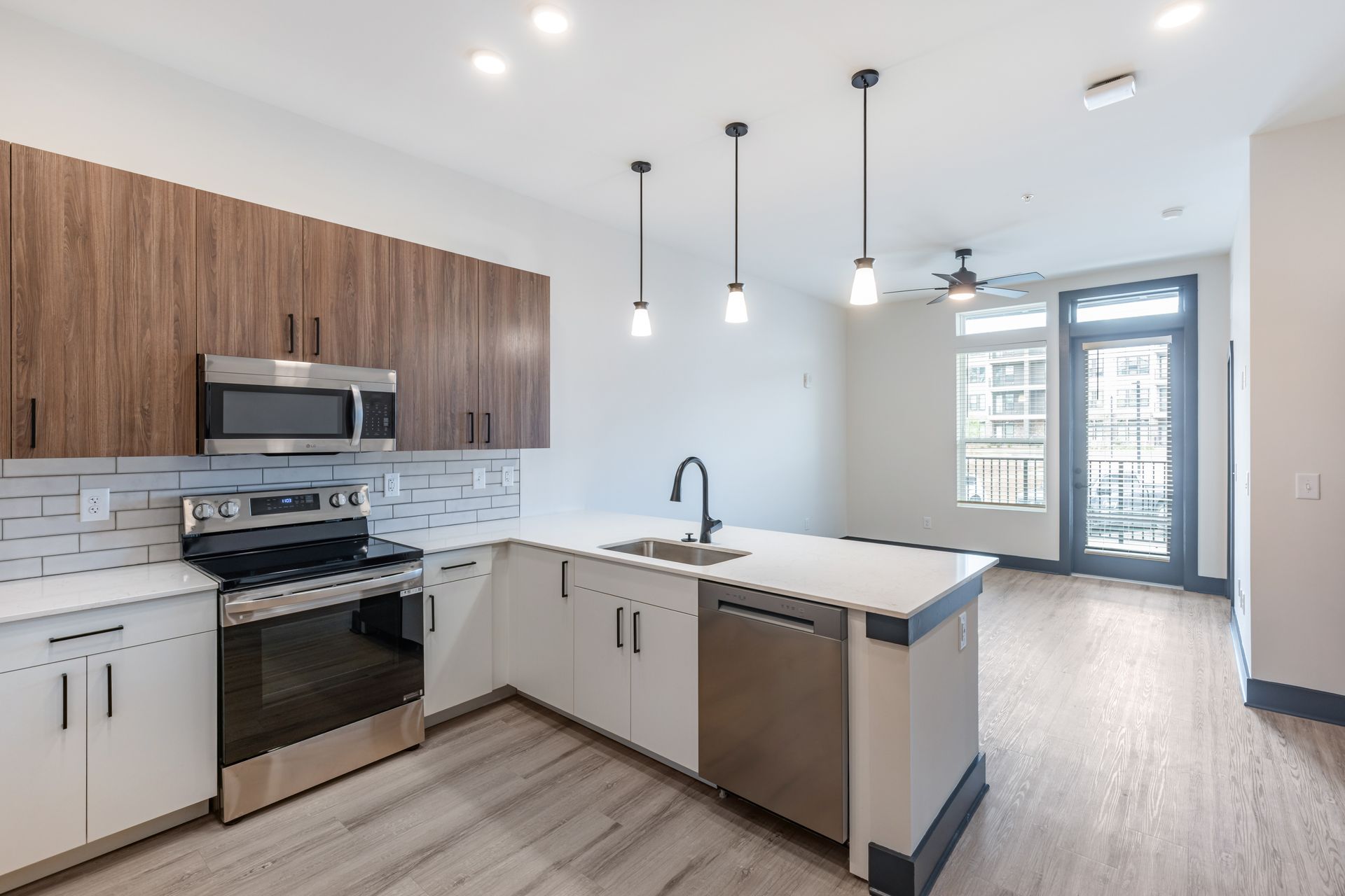 Bright modern kitchen with white island, wood cabinets, stainless steel appliances, and pendant lights at Vela Park apartments in East Lake, Atlanta, GA.