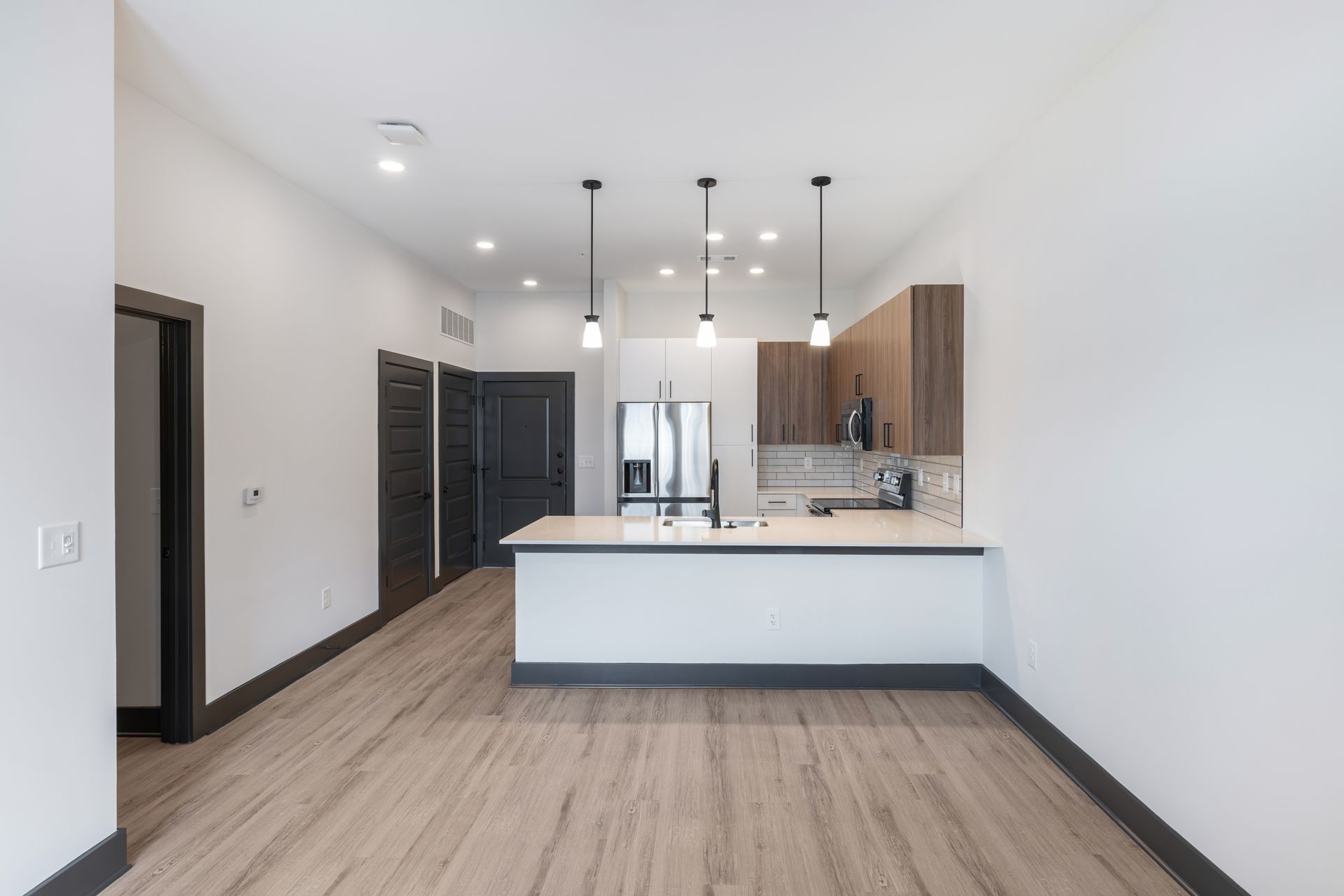 Modern open-plan kitchen with white island, dark cabinets, and wood flooring at Vela Park apartments in East Lake, Atlanta, GA.