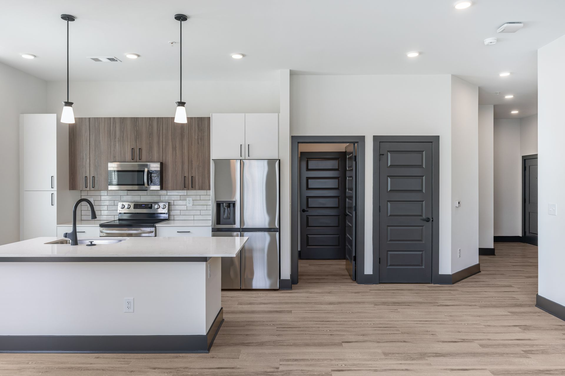 Modern open-concept kitchen with white island, gray cabinets, stainless appliances, and pendant lights at Vela Park apartments in East Lake, Atlanta, GA.