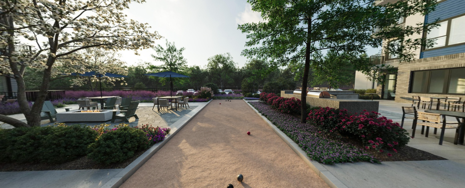 Courtyard walkway lined with flower beds and trees between modern buildings at Vela Park apartments in East Lake, Atlanta, GA.