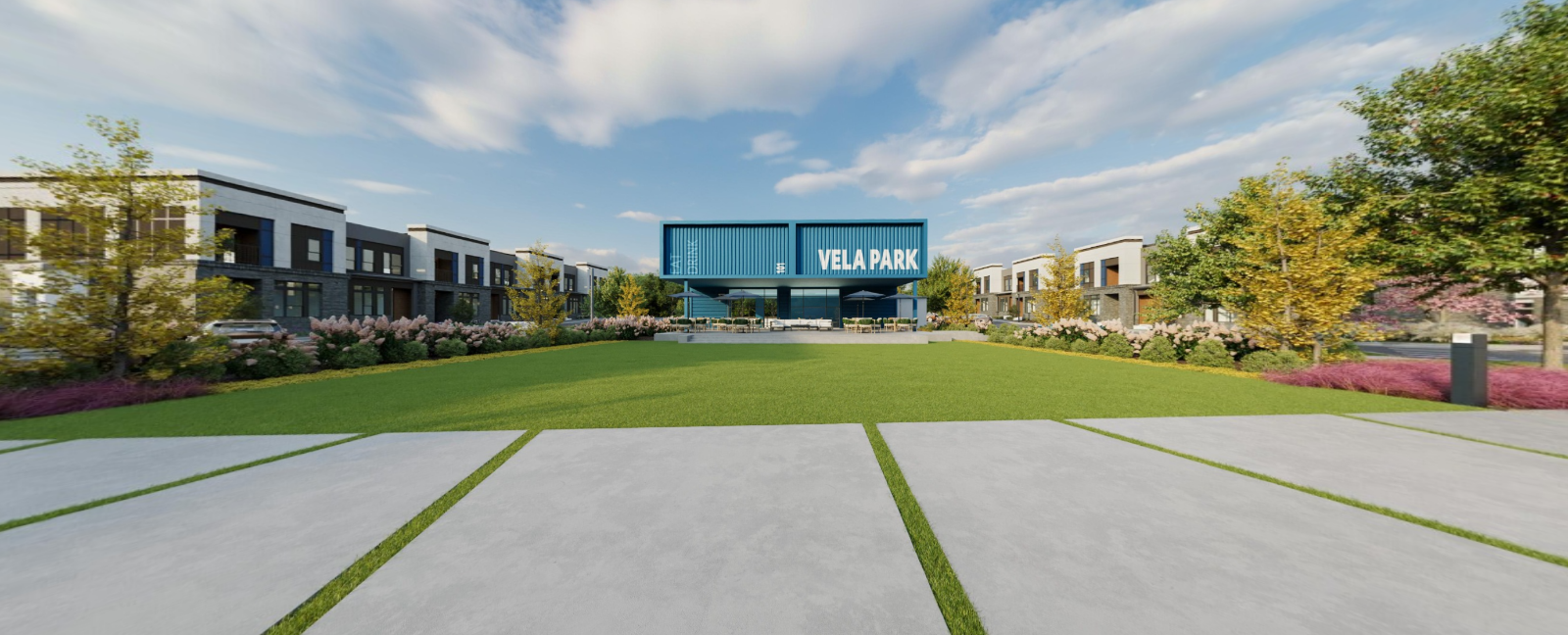 Wide campus lawn facing modern buildings with a central blue sign under a cloudy sky at Vela Park apartments in East Lake, Atlanta, GA.