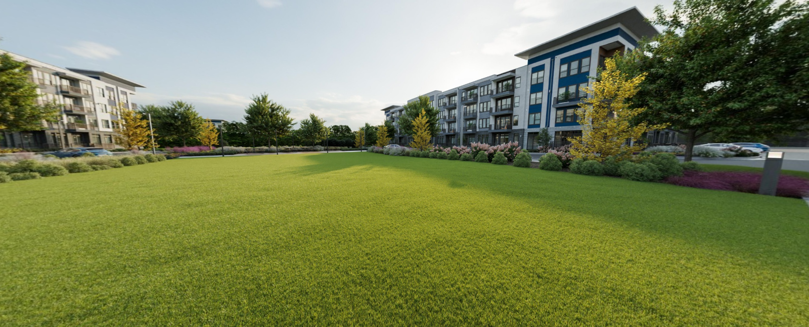 Wide grassy lawn in a modern apartment courtyard with buildings and trees around the edges at Vela Park apartments in East Lake, Atlanta, GA.