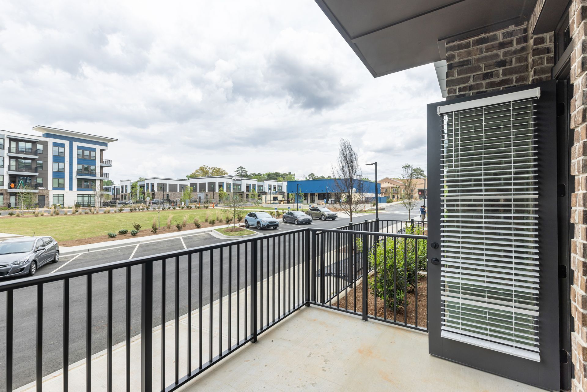 Apartment balcony overlooking a street and modern buildings on a cloudy day at Vela Park apartments in East Lake, Atlanta, GA.