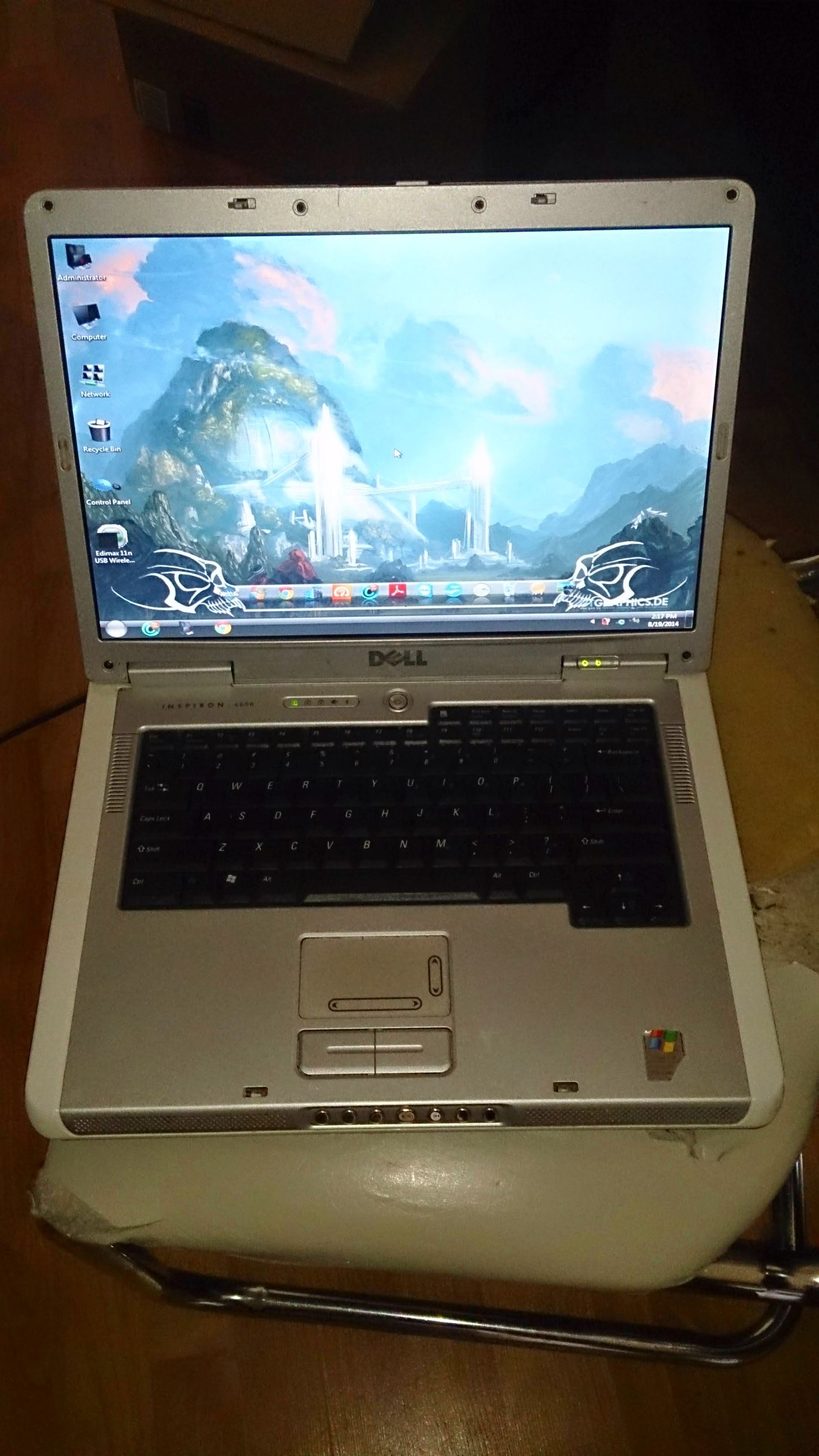Silver Dell laptop, open, displaying a mountain scene wallpaper, on a chair.