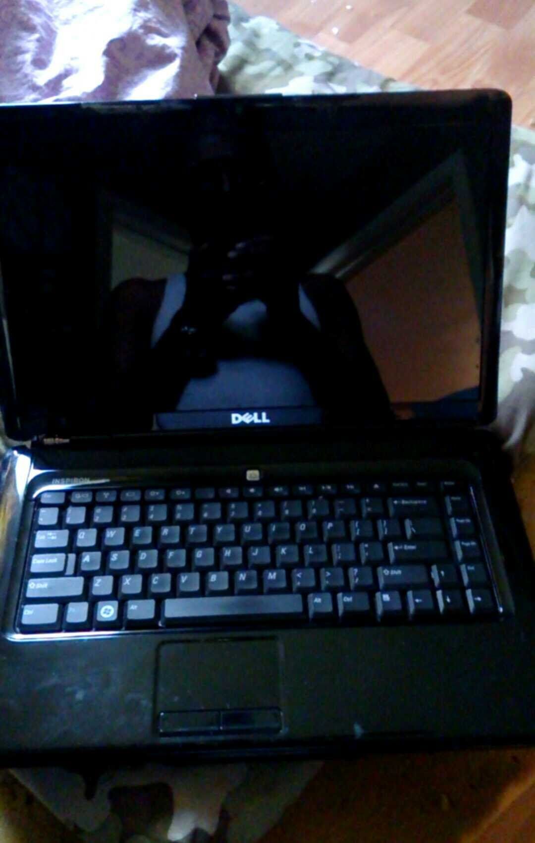 Black Dell laptop displaying the Dell logo on the screen, reflecting the room.