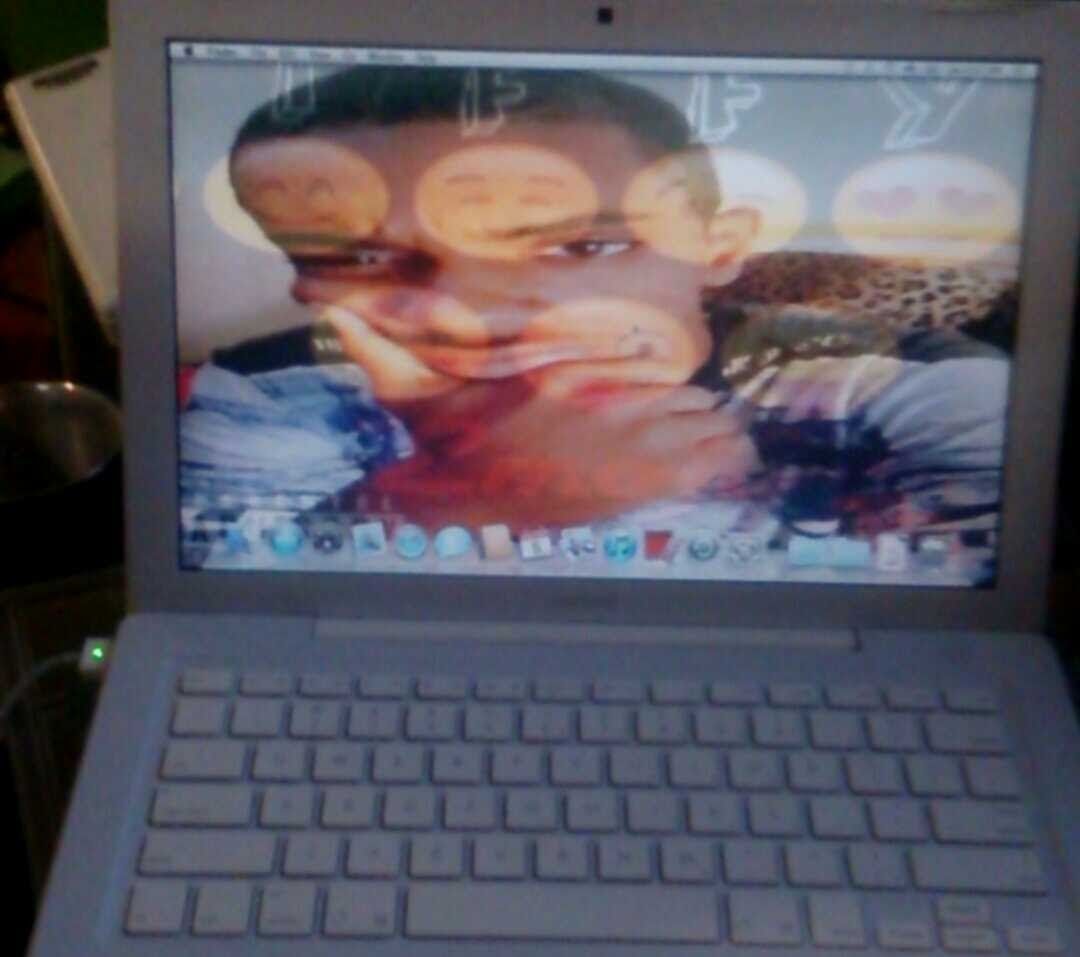 White laptop displaying a person's face on the screen. The person is holding their chin.