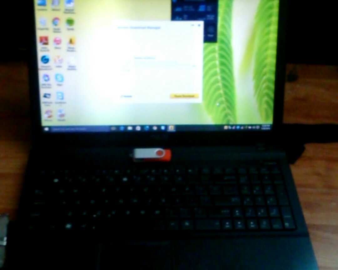 Black laptop displaying a window with text on a desk, a USB drive is inserted.