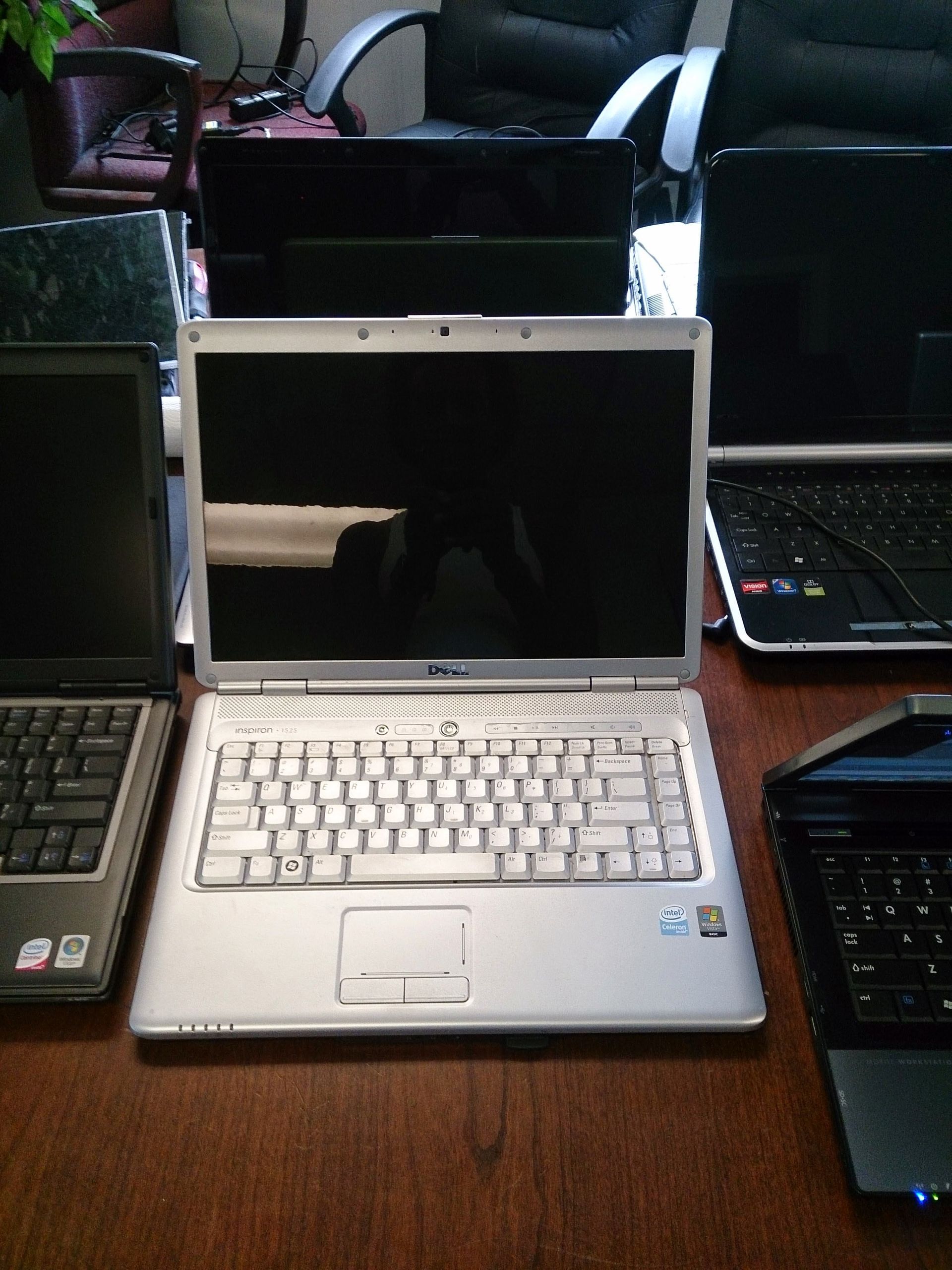 Silver laptop open on a table, surrounded by other laptops.