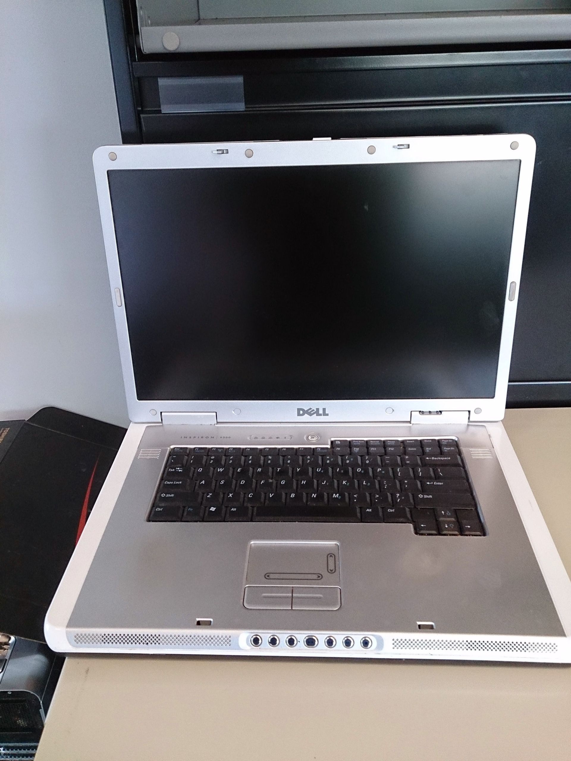 Dell laptop with a black screen and silver frame sitting on a table.