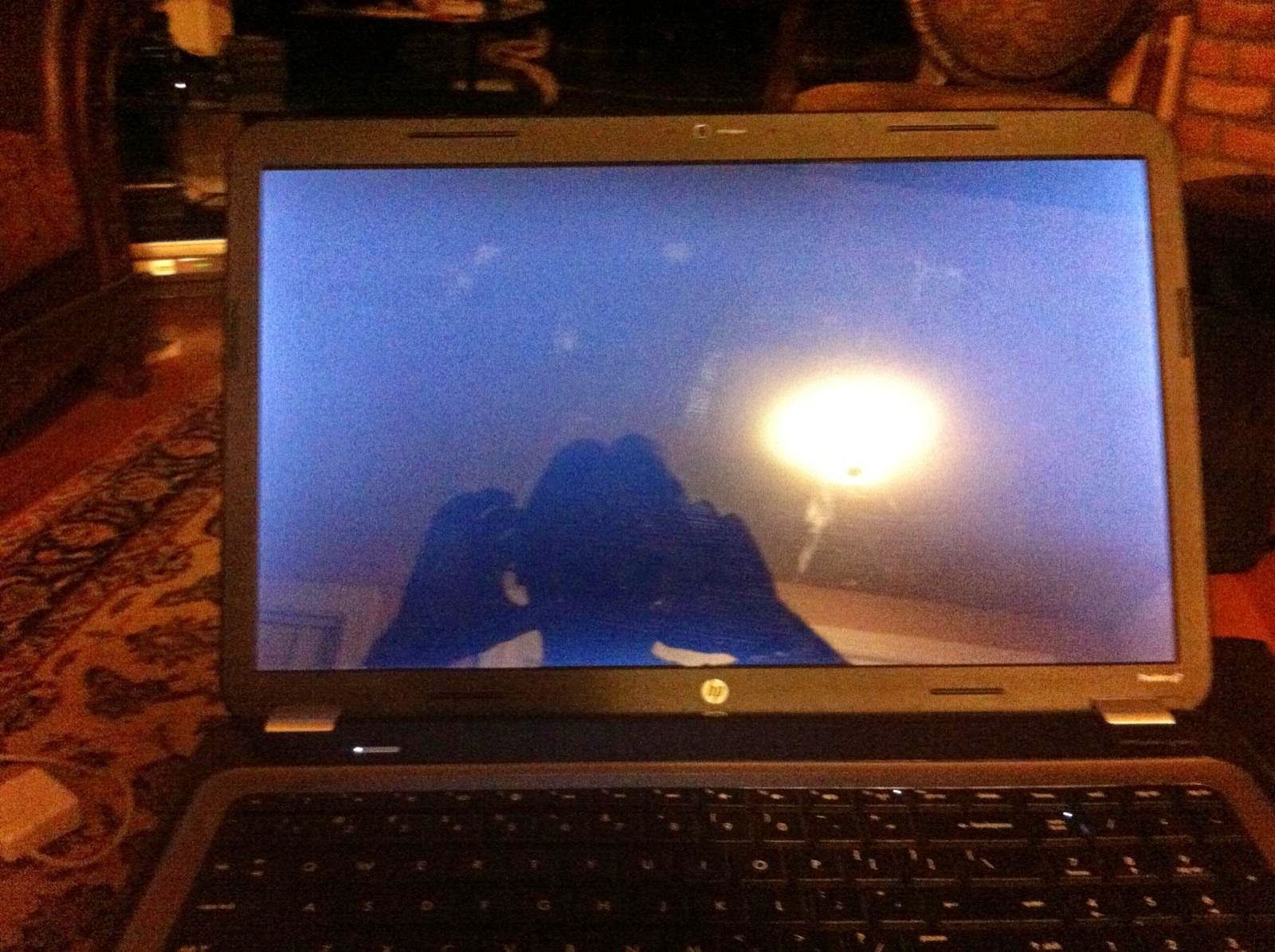 Laptop screen reflecting a person's silhouette with bright light. Dark keyboard, HP logo visible.