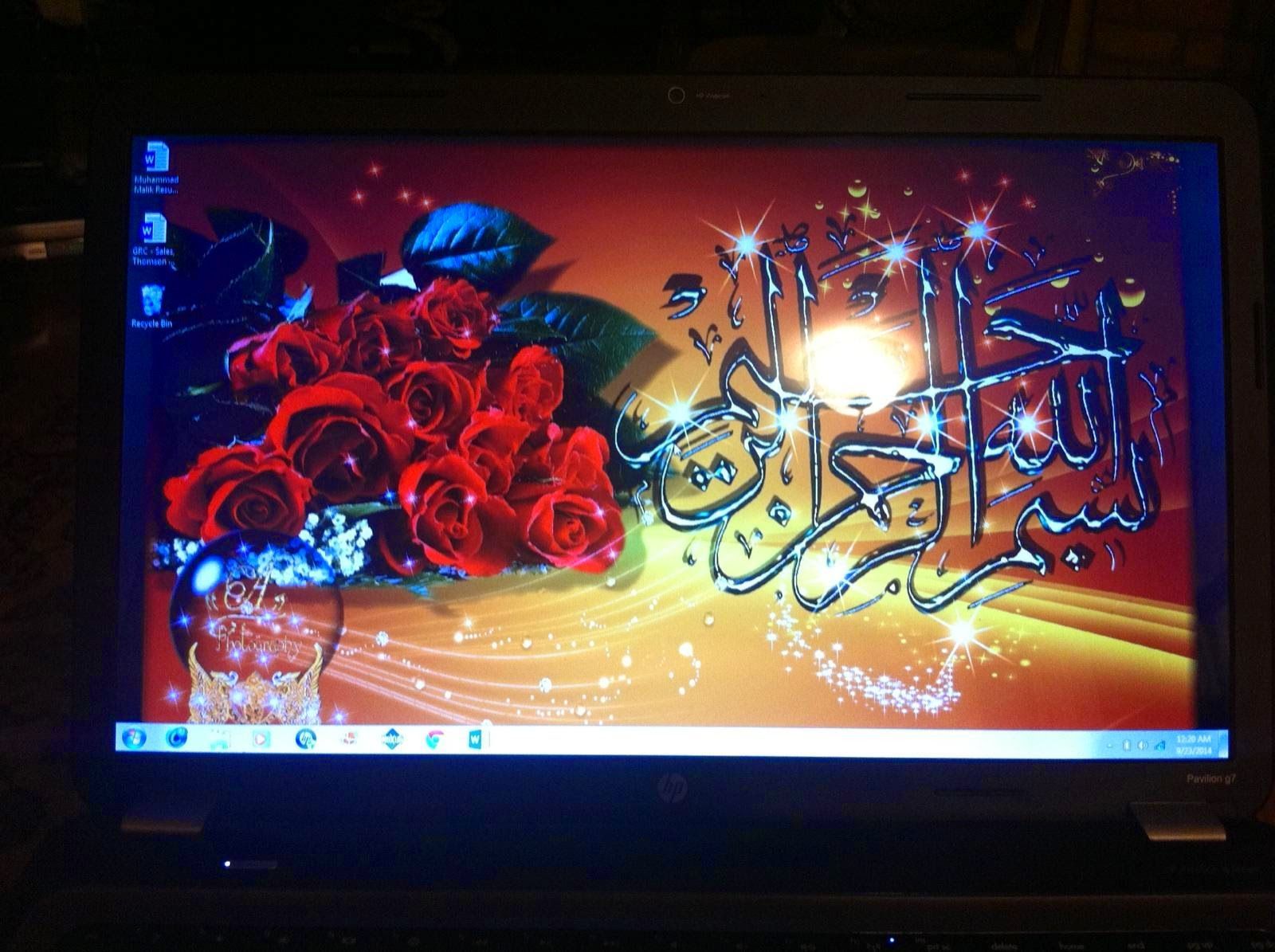 Laptop screen displaying roses and Arabic calligraphy.