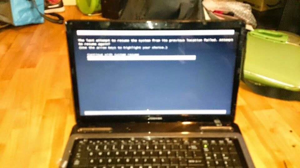 Toshiba laptop with a blue screen and white text on a wooden surface.