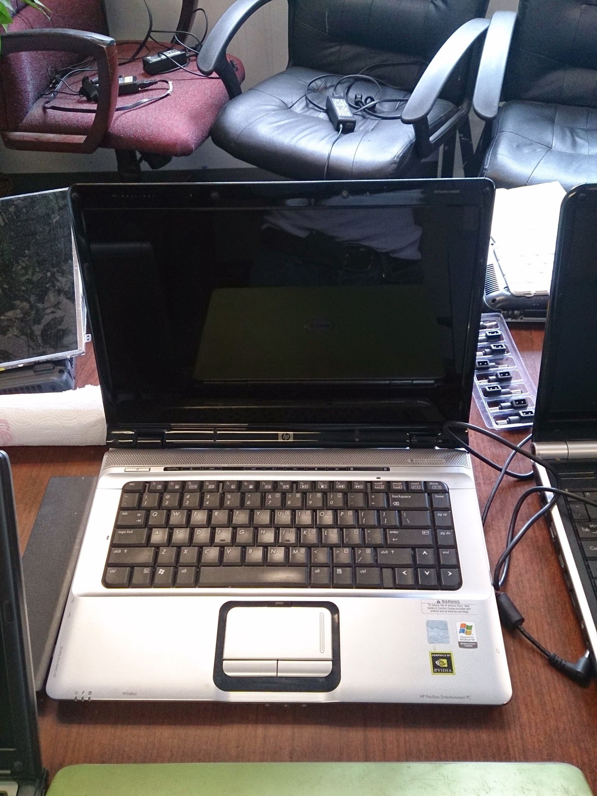 HP laptop on a desk, keyboard visible, screen turned on, surrounded by other laptops.
