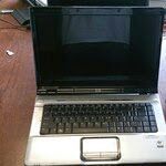 Laptop computer on a wooden surface, open with a black screen and keyboard visible.