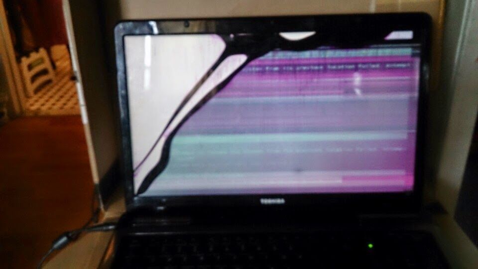 Broken Toshiba laptop screen displaying colorful horizontal lines and a damaged corner.