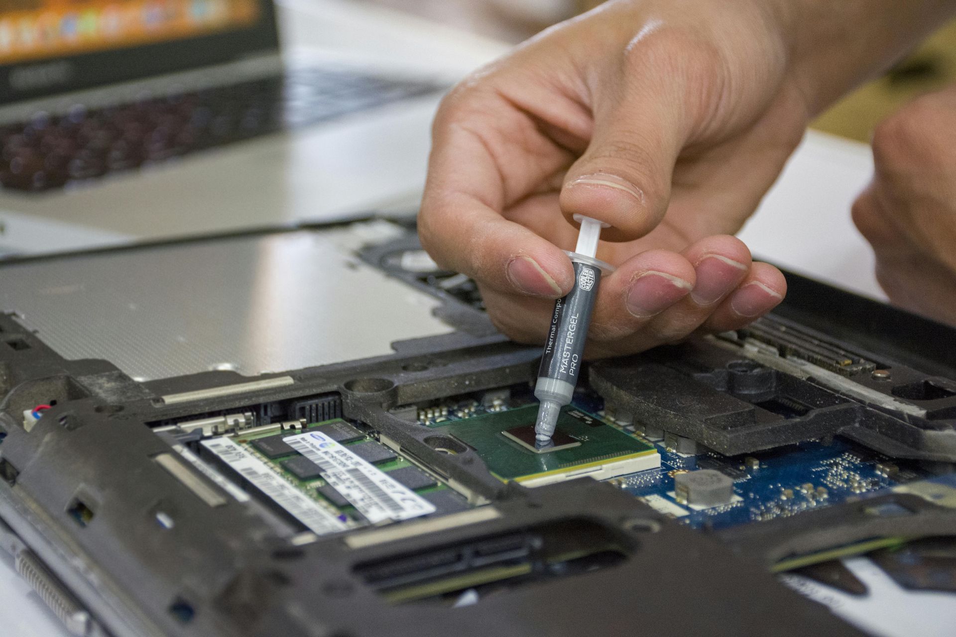 Person applying thermal paste to a laptop CPU.