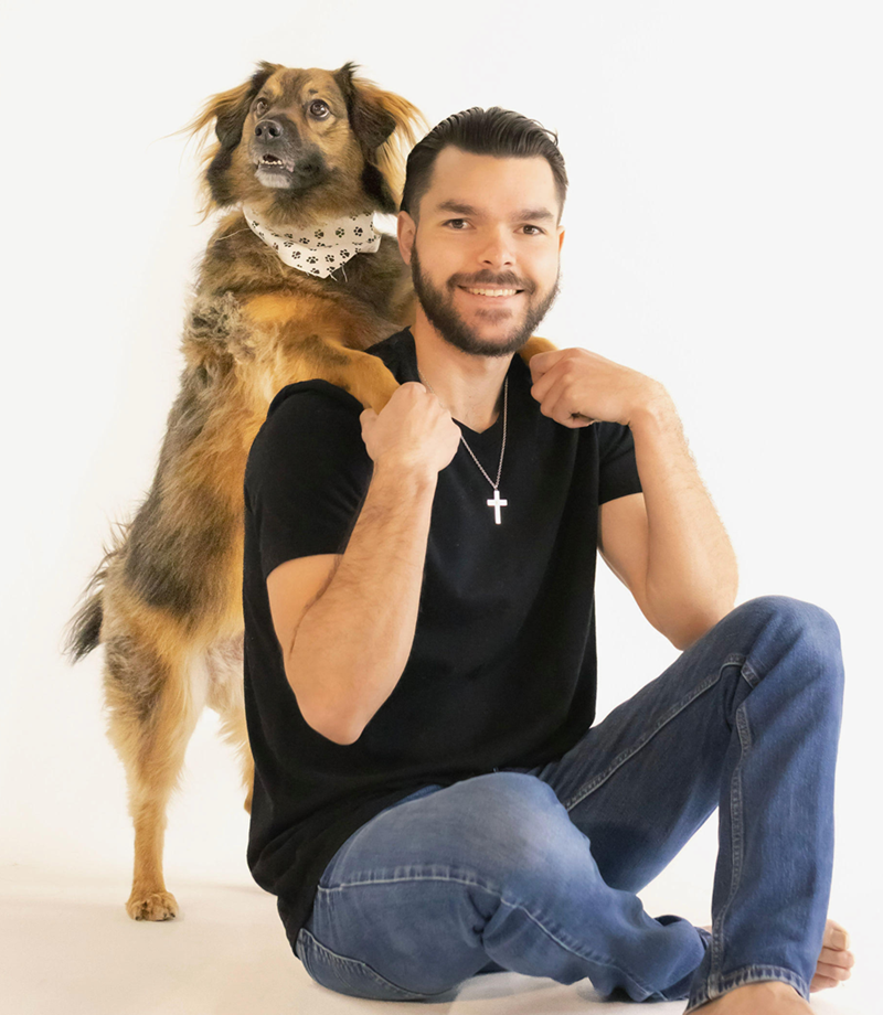 A man is sitting on the floor with a dog on his back
