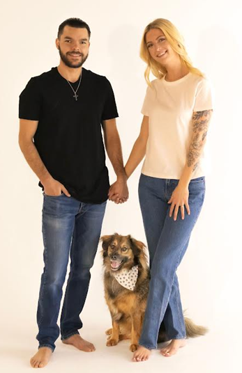 A man and a woman are holding hands while standing next to a dog.