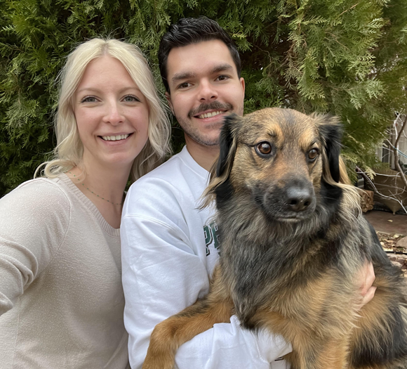 A man and a woman are posing for a picture with their dog.